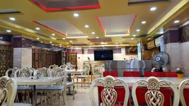 دو نان تازه کنار بشقاب غذا، سبزی و کاسه‌ای مسی روی میز