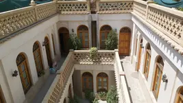 حیاطی از قصر منشی با گل‌های رنگی و درختان سبز