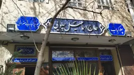 سالن رستوران با دیوارهای فیروزه‌ای، میزهای چوبی و تابلوهای نقاشی چهره