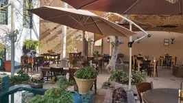 عمارتی تاریخی با حیاط بزرگ، حوض آبی و میزهای زیر سایبان
