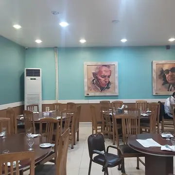 ایوان و پنجره‌های چوبی یک خانه تاریخی با حیاطی پر از گیاه
